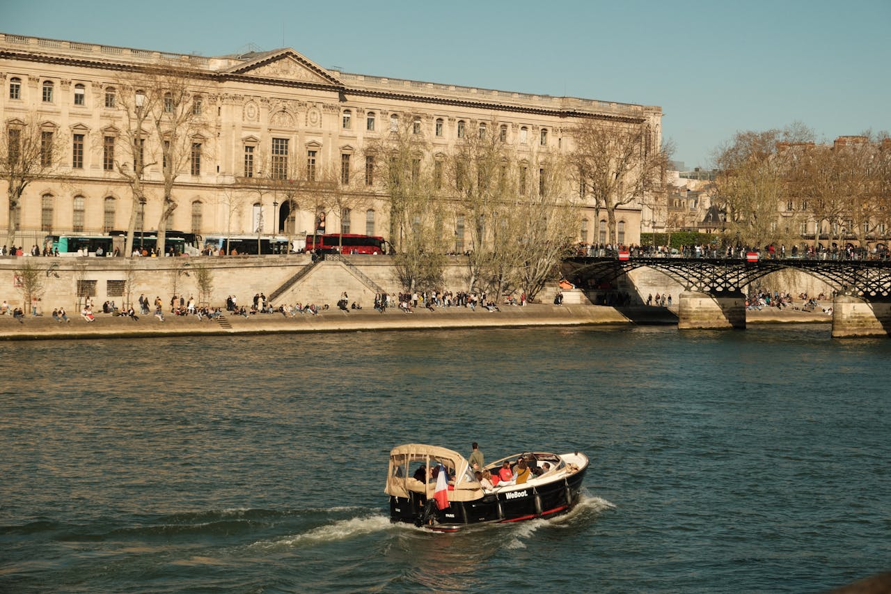 A scenic view of the Seine River with a boat and historic architecture in Paris.